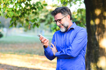 Wall Mural - Senior man websurfing on tablet outside the house. Senior mature man walking using tablet pc. Senior man uses his digital tablet. Older man using tablet computer in park