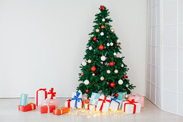 Christmas tree with lights garlands and new year gifts interior white room