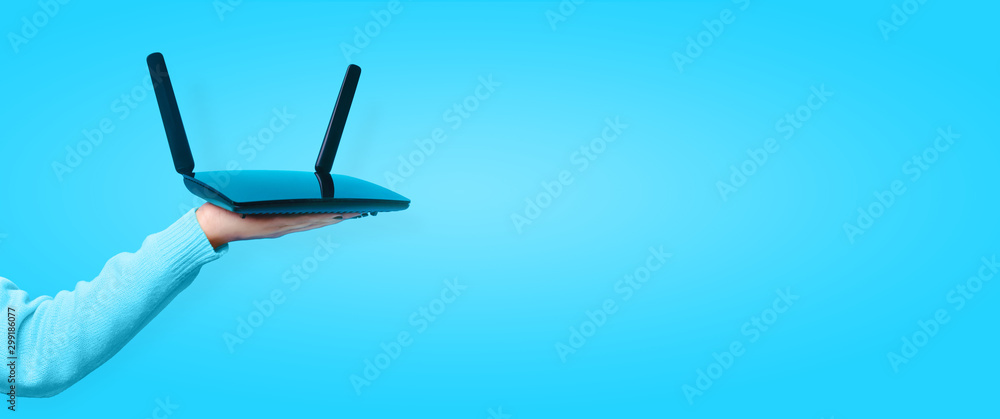 black wifi router on hand over blue background, panoramic mock up image - obrazy, fototapety, plakaty 