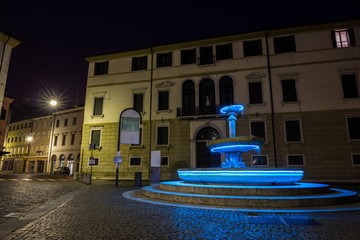 Fountain illuminated in blue in city center at night Treviso Italy