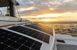 Solar powered catamaran at sunset, fully sustainable and powered by solar energy, charging batteries aboard a sailboat, vessel in ocean waters, nobody. Photovoltaic panels renewable eco energy concept