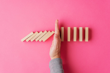 Top view of male hand interrupting collapsing dominos