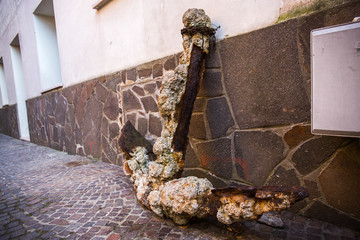 Stone ancient anchor standing near a wall of a building