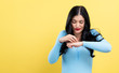 © Tierney - Young woman scratching her itchy arm. Skin problem. on a yellow background