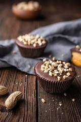 Wall Mural - Cold crunchy treat, chocolate cups with caramel and peanut butter filling, sprinkled with chopped nuts