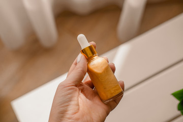 Woman holds in hand one glass cosmetic bottle