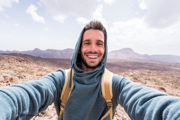 handsome hiker taking a selfie hiking a mountain using his smartphone