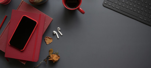Top view of dark luxury workspace with red notebooks and copy space with office supplies