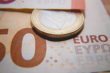 Macro photo of a coin in 1 Euro on a blurred background banknote in 50 euro. Money background. Extremely small depth of field.