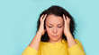 © yavdat - Young Asian girl scratches her hair on a blue background. headache