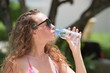 © tharathip - Beautiful girl in a bathing suit is drinking water from a bottle