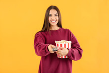 Young Woman With Popcorn And Remote Control On Color Background