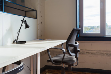 Loft style office with white brick walls and concrete columns. There is a meeting area with a large white table with black chairs