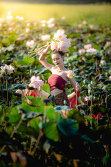 Wall Mural - Asian woman collecting lotus flowers and she wear Traditional Thai dresses, Thailand