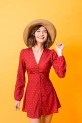 Wall Mural - Asian girl wearing red dress with brown hat over orange background.