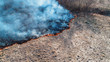 © nordroden - Forest and field fire. Dry grass burns, natural disaster. Aerial view. The camera hangs motionless at low altitude.