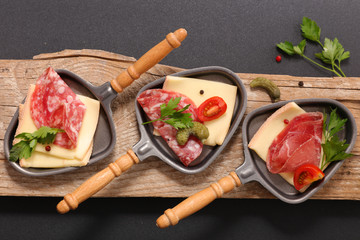 Wall Mural - spoon with raclette cheese, salami and herb