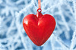 Heart shaped Christmas decorations on branches covered with ice and snow as background