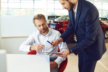 Wall Mural - A man buys a car in a car showroom.