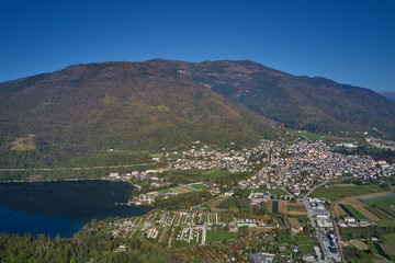 Aerial view of Lake Levico north of Italy. In the background the trees, Alps, blue sky. Reflection of mountains in water. Autumn season. Multi-colored palette of colors