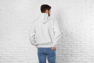 Wall Mural - Young man in sweater at brick wall. Mock up for design