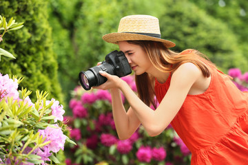 photographer taking photo of blossoming bush with professional camera in park