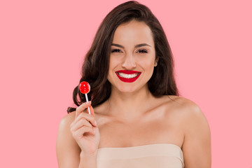 Wall Mural - happy woman with red lips holding lollipop isolated on pink