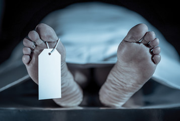 Cadaver on autopsy table at morgue, label tied to toe, close-up