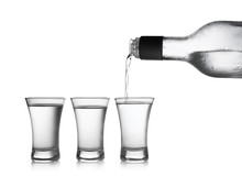 Pouring Cold Vodka Into Shot Glass On White Background