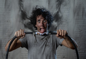 Funny image of man getting electric shock with funny face and smoke all around. DIY concept