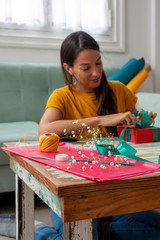 Woman wrapping handmade craft gifts on the table at home