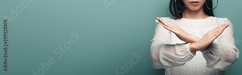 Fotomural cropped view of brunette asian woman showing stop gesture on green background, p