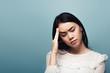 © LIGHTFIELD STUDIOS - upset brunette asian woman with headache on blue background