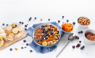 chocolate oatmeal porridge with blueberry, nuts, banana, dried apricot for healthy breakfast. Top view