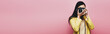 © LIGHTFIELD STUDIOS - asian woman in yellow outfit taking picture on digital camera isolated on pink, panoramic shot
