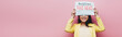 © LIGHTFIELD STUDIOS - panoramic shot of happy asian woman in yellow outfit holding newspaper with fake news isolated on pink
