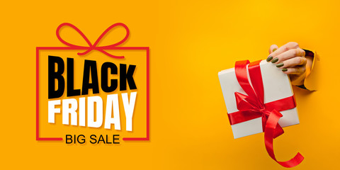 Hands holding gift box with black friday lettering on yellow background. Concept of sales, black friday, cyber monday, finance, business, money. Online shops and payments bill.