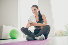 Full Length Photo Of Positive Active Energtic Sportswoman Sit On Purple Mat Use Cellphone Post Sport Comments In Healthy Sportive Blogs Wear Sneakers Gray Pants In Gym Like House