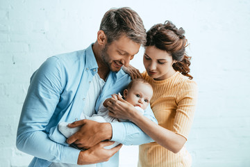 Wall Mural - attractive woman standing near happy husband holding little child
