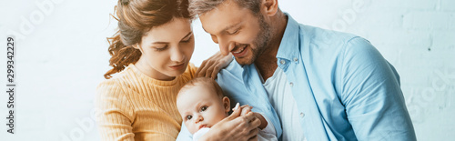 Fotografía shot of happy parents smiling while holding little daughter together