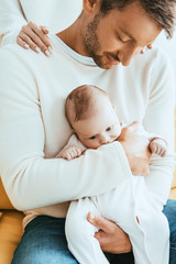 Wall Mural - partial view of woman touching shoulders of husband holding adorable infant