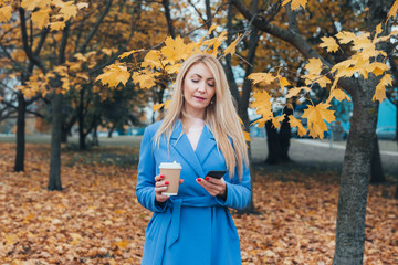 Successful middle aged woman female using mobile cell phone for texting or social media in autumn park