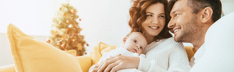 Wall Mural - happy man looking at smiling wife holding adorable baby