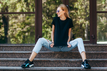 Poster - Girl wearing black t-shirt, glasses and leather jacket posing against street , urban clothing style. Street photography