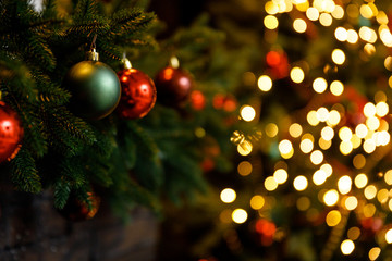 Christmas and New Year interior - blur background: fireplace, lamps, green Christmas tree, brown leather sofa, gifts, candles, moose rocking chair.  Lots of lights glowing in the dark.