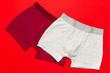 Men's underwear, red burgundy and gray underpants on red background flat lay top view copy space. Fashion blog, natural underwear, advertising, shopping concept. Pants boxers