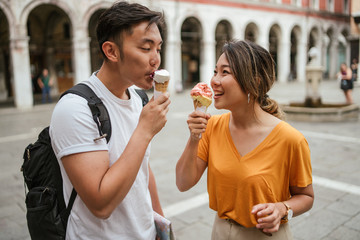 Portrait of a young and beautiful Asian couple eating ice cream in a square in the city of Venice, Italy - Millennials on their honeymoon