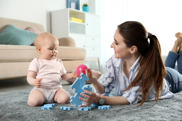 Canvas Print - Happy mother playing with little baby on floor indoors