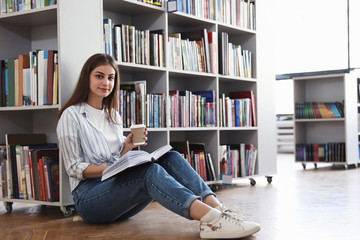 Wall Mural - Young woman with book on floor in library