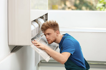 Wall Mural - Professional technician maintaining modern air conditioner indoors